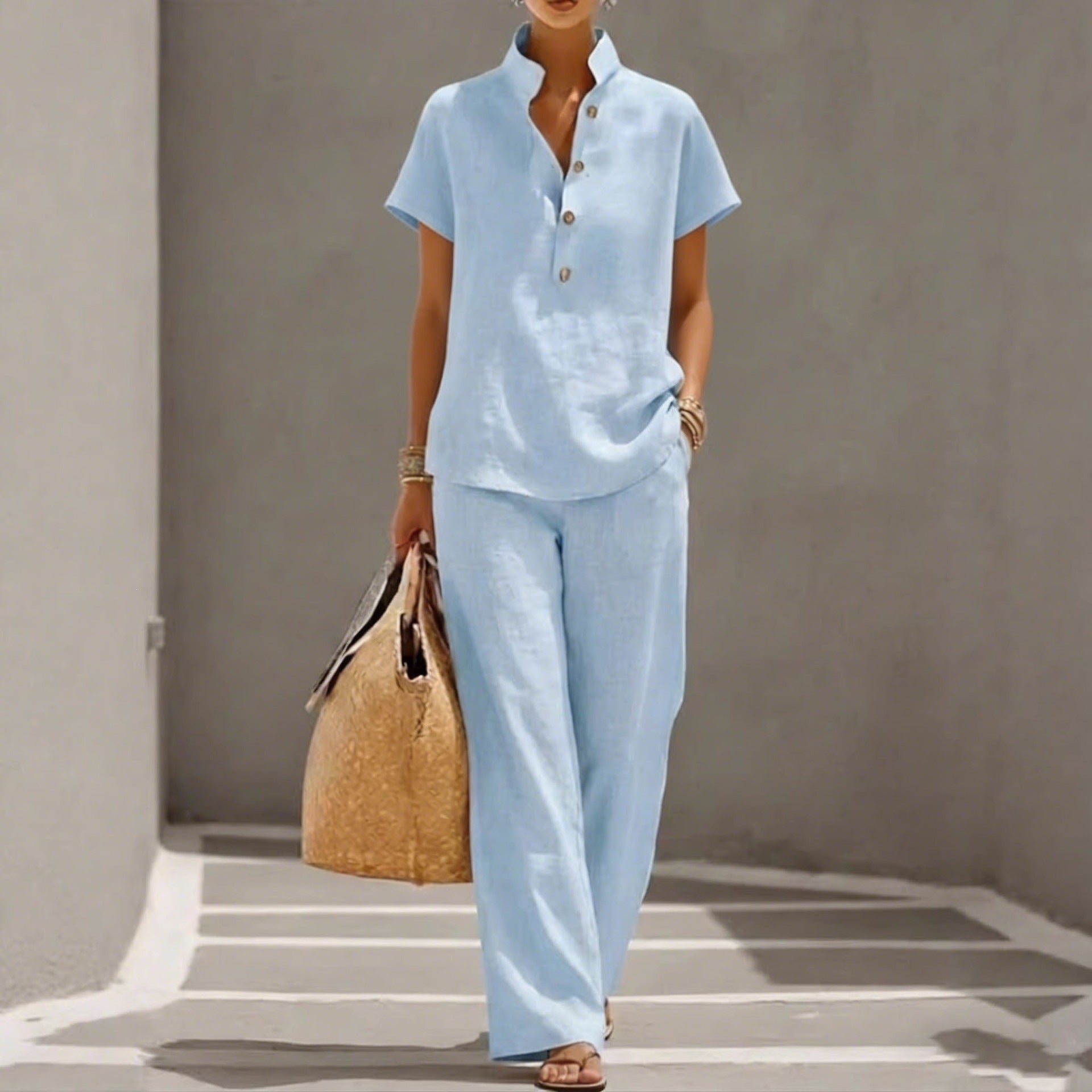 Person wearing a light blue outfit holding a woven bag against a neutral background