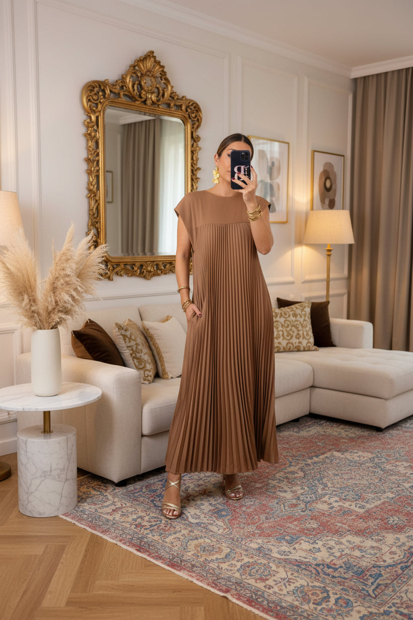 Woman wearing a brown pleated dress in a room with decor elements.