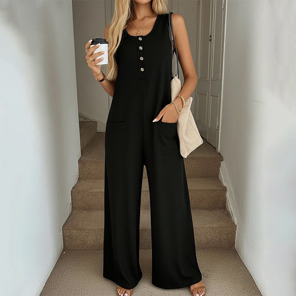 Woman in a black jumpsuit holding a coffee cup on a staircase.