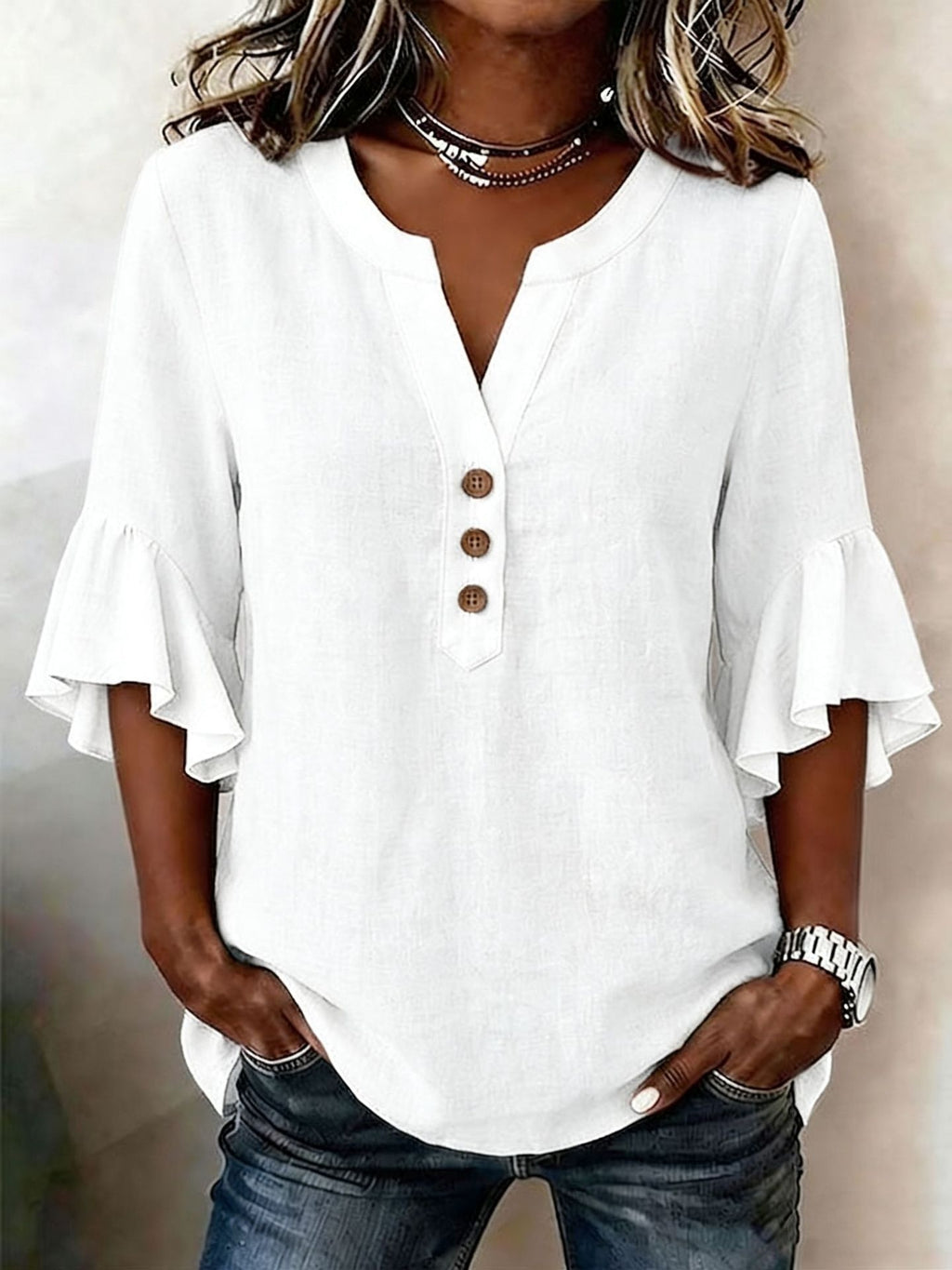 White blouse with ruffled sleeves worn by a person on a neutral background