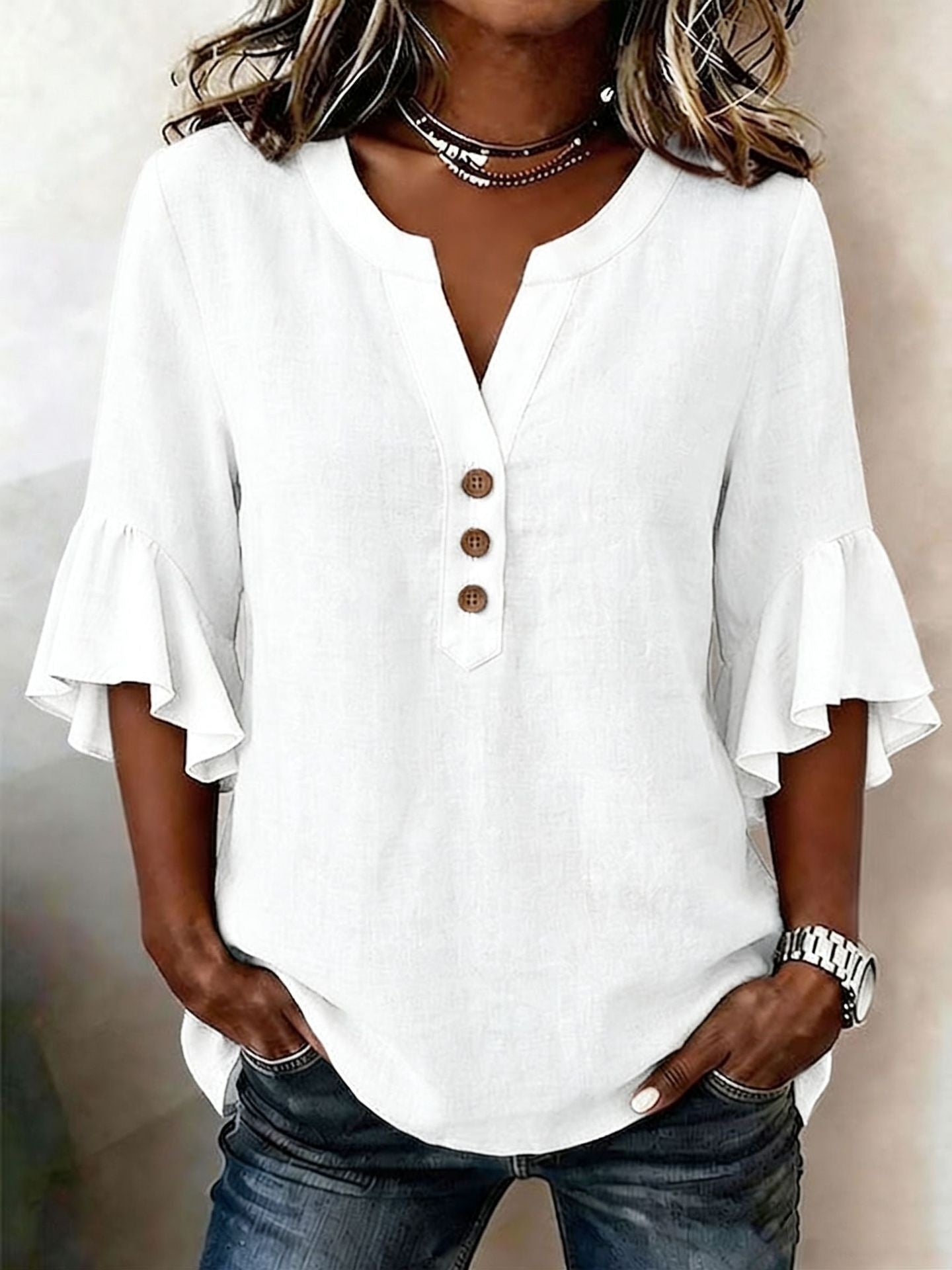 White blouse with ruffled sleeves worn by a person on a neutral background