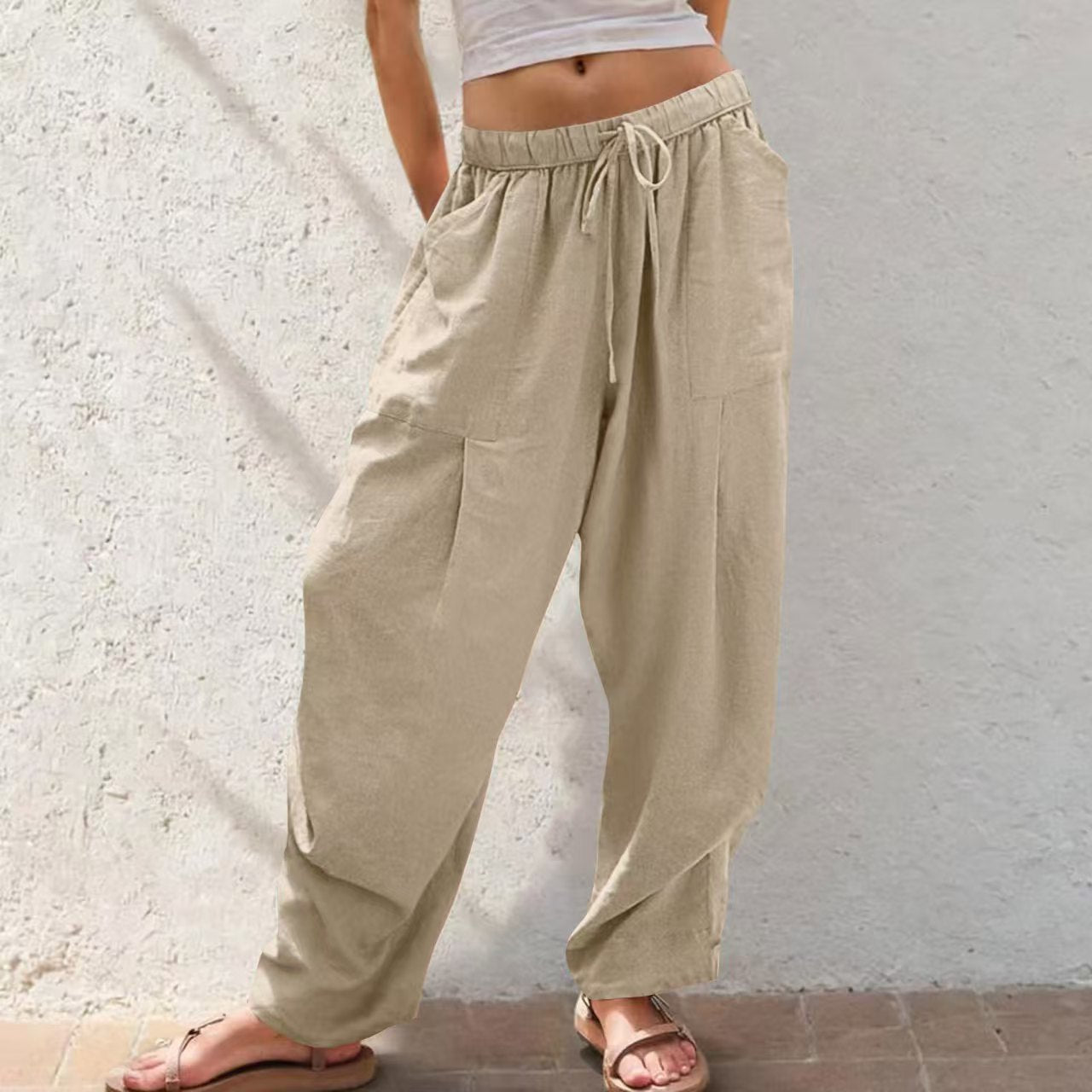 Beige wide-leg pants worn by a person against a light-colored wall.