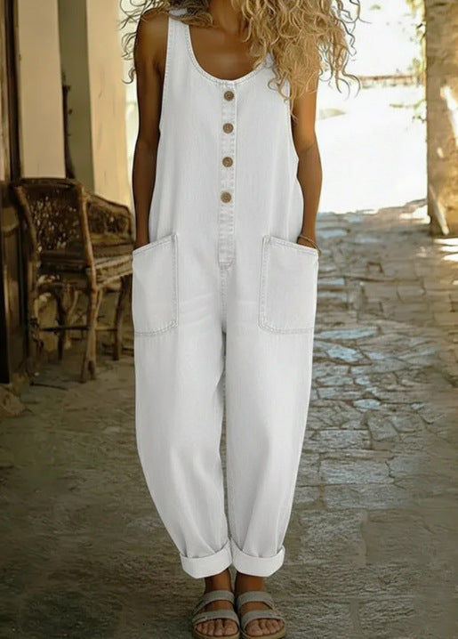 Woman wearing a white sleeveless jumpsuit with button details on a stone path.