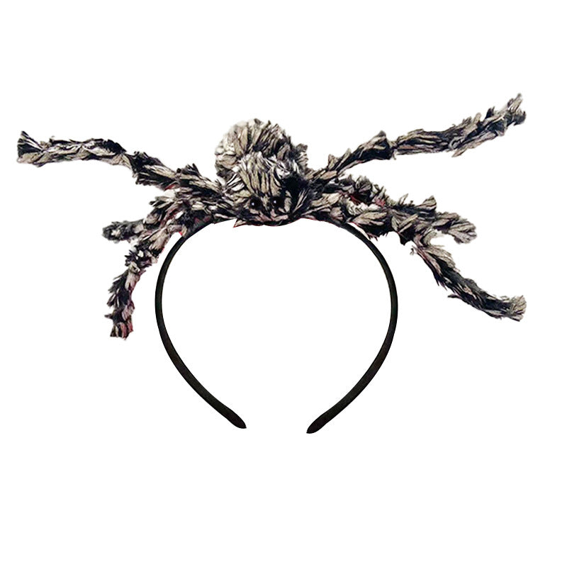 A spider-themed headband featuring a black plastic band with a large, textured spider body and eight spiky, frayed legs in a black, white, and gray mottled pattern, shown against a plain white background.