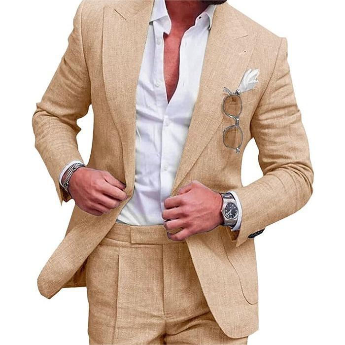 Man wearing a beige suit with a white shirt, sunglasses in the pocket, and a watch on a white background.