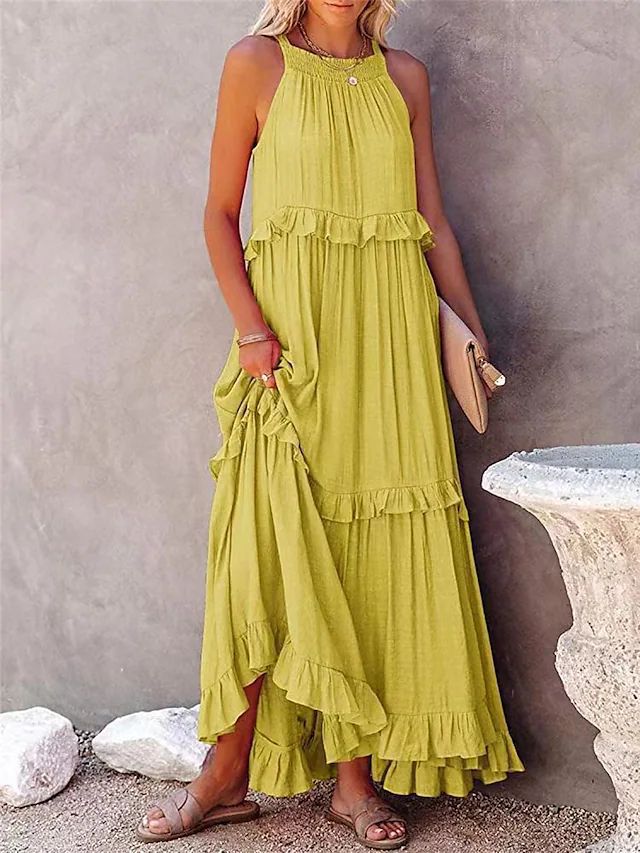 Woman wearing a green tiered dress against a neutral background