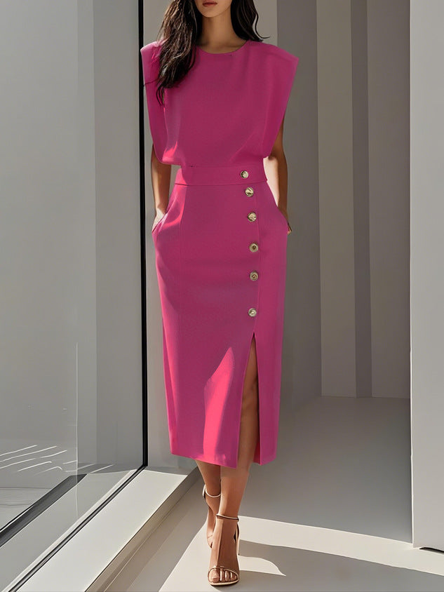 Woman wearing a pink dress with buttons standing in a modern indoor setting.