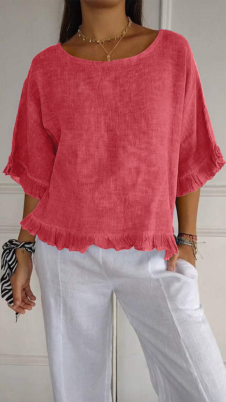 Person wearing a pink linen top and white pants against a neutral background