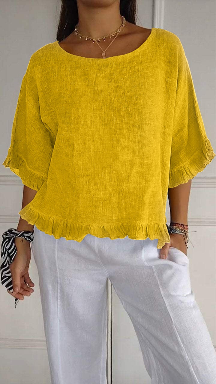 Person wearing a yellow blouse and white pants against a neutral background