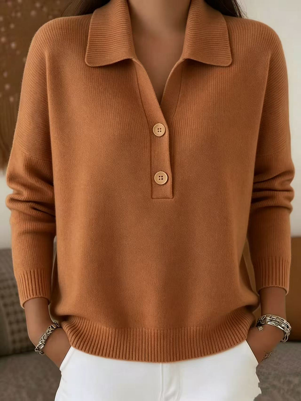 Brown sweater with button details worn by a person, blurred background