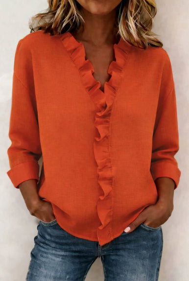Person wearing an orange ruffled blouse and blue jeans against a white background