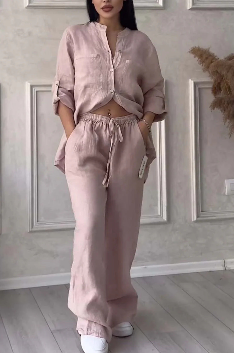 Person wearing a pink outfit in a room with framed pictures on the wall.