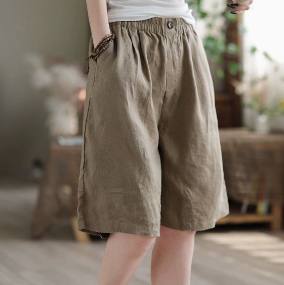 Person wearing brown linen shorts in a blurred indoor setting