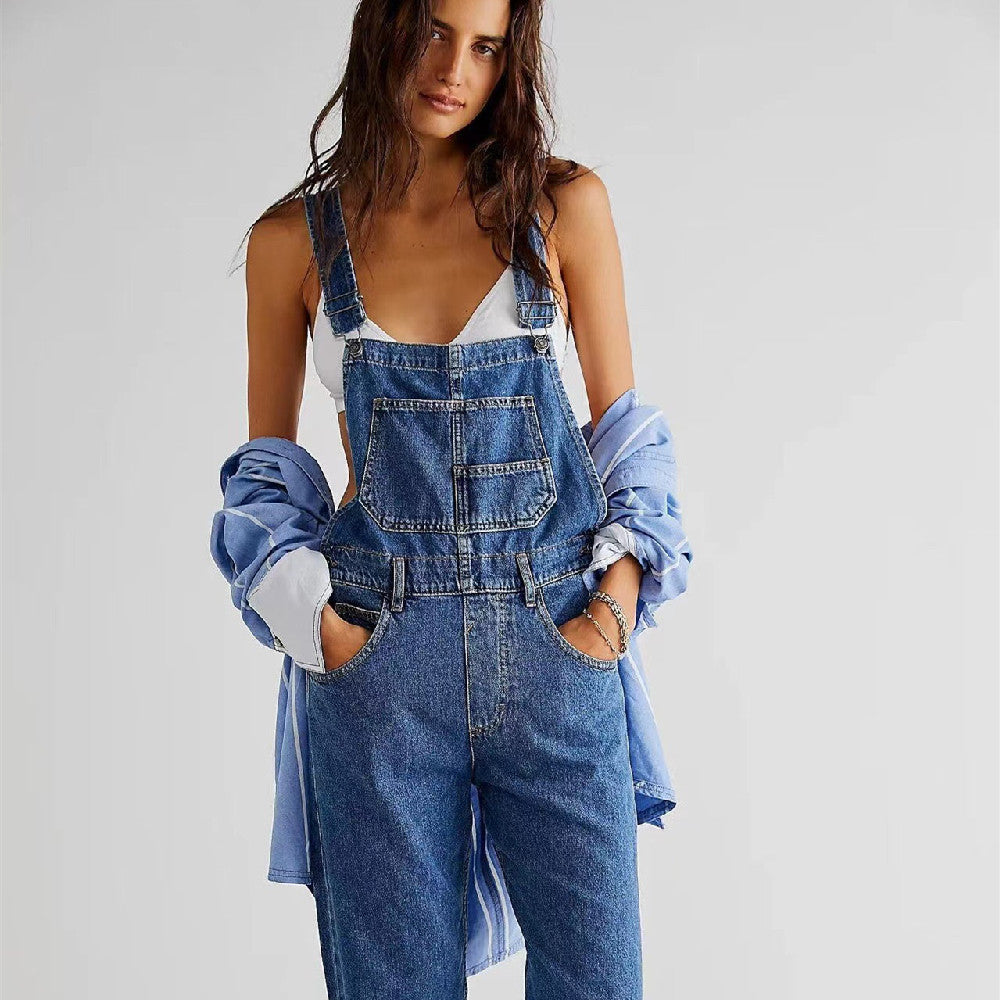 Woman wearing denim overalls with a plain background