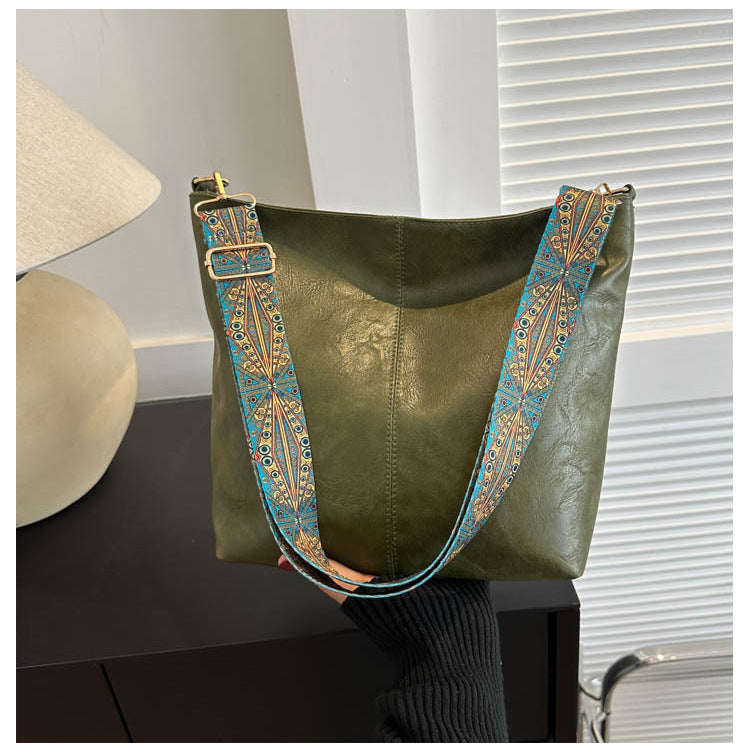 Green leather handbag with decorative strap on a table