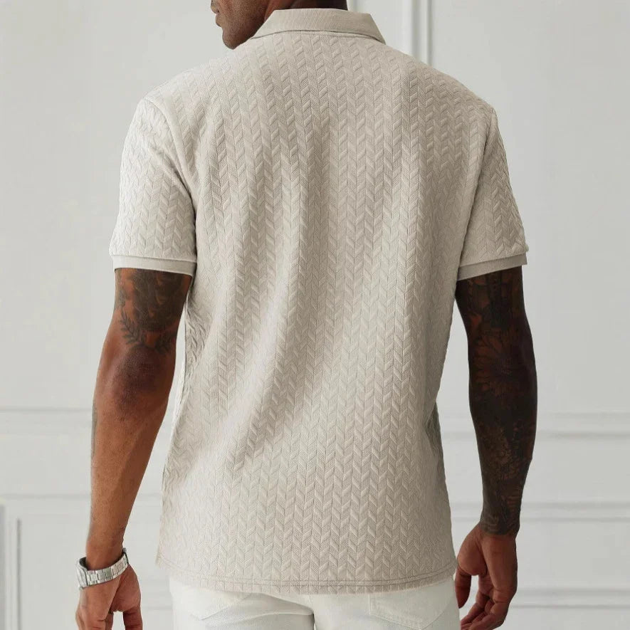 Man wearing a beige patterned polo shirt with a white background