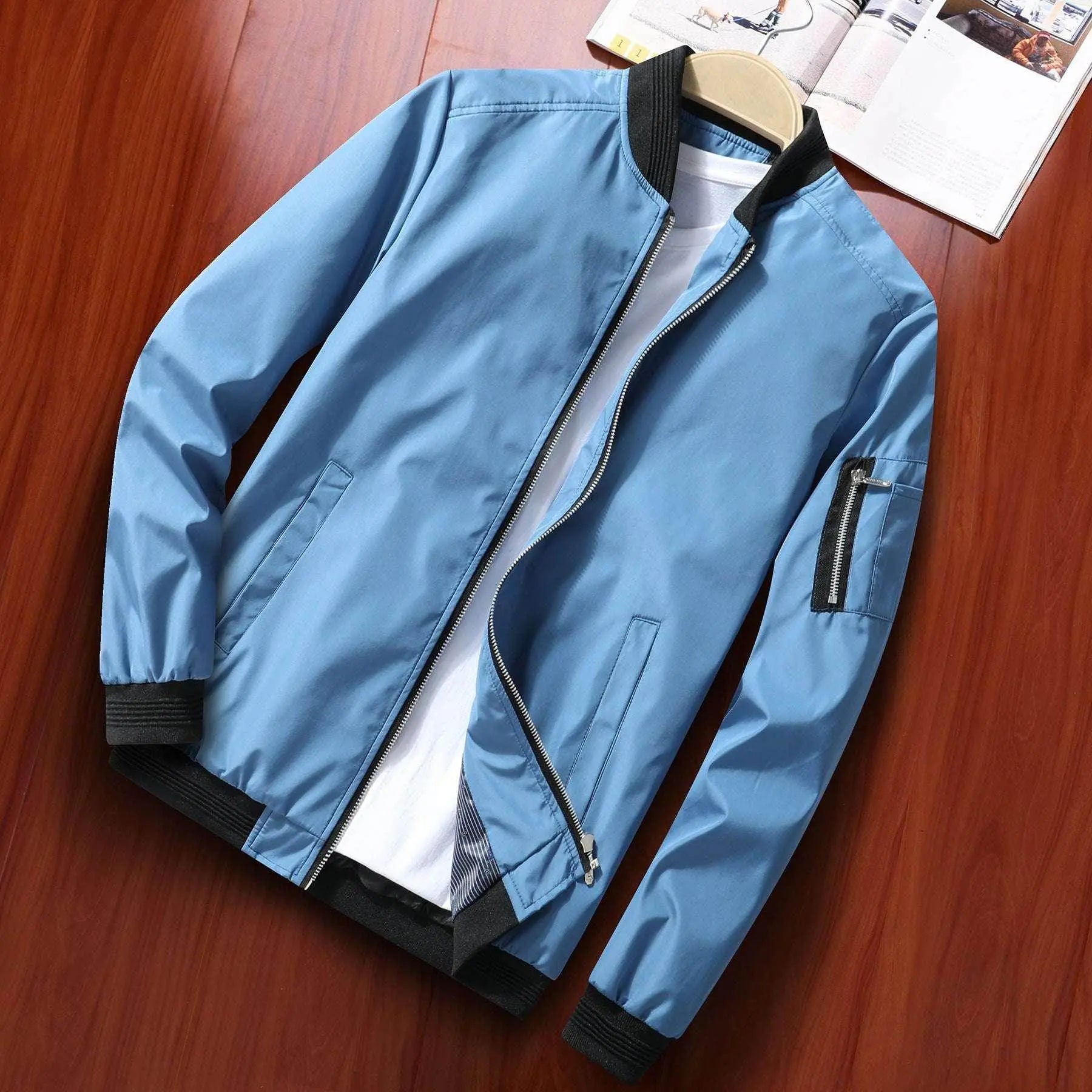 Loose fit men's blue baseball jacket with black trim from ZA-Zola on wooden surface