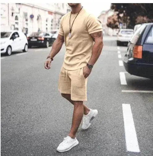 Man wearing beige summer sportswear set with t-shirt and shorts from ZA-Zola, walking in city street