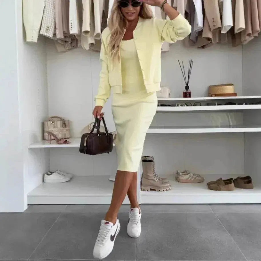 Woman in pastel yellow two-piece knit dress and cardigan set, white sneakers, holding handbag, in modern boutique closet, ZA-Zola fashion.