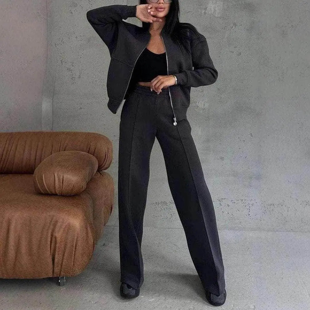 Woman modeling black zipper jacket and wide-leg pants 2-piece set from ZA-Zola, modern interior