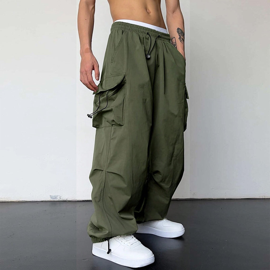 Person wearing olive green cargo pants and white sneakers on a plain background