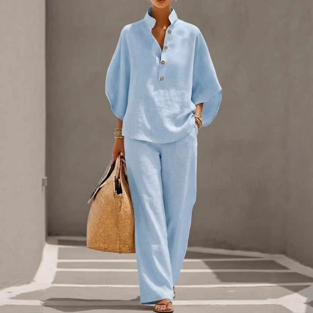 Person wearing a light blue outfit holding a woven bag against a neutral background