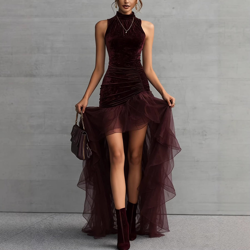 Woman wearing a burgundy velvet dress with sheer overlay against a gray background