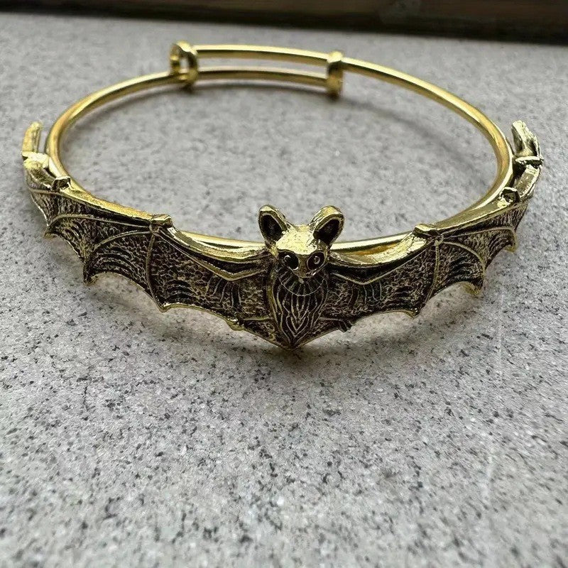 Gold bat-shaped bracelet on a gray surface
