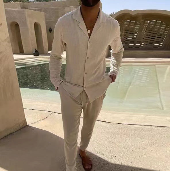 Man in a white outfit standing by a pool with architectural elements in the background