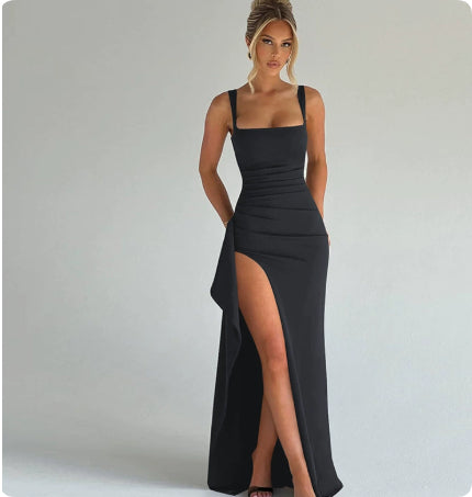 Woman wearing a black evening gown with a high slit on a plain background