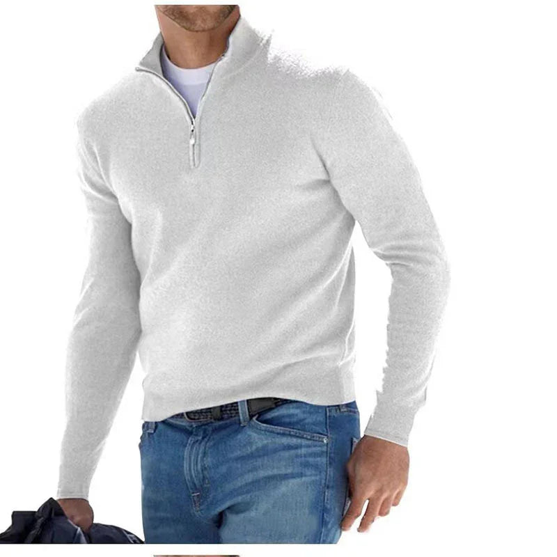 Man wearing a gray half-zip sweater and blue jeans on a white background