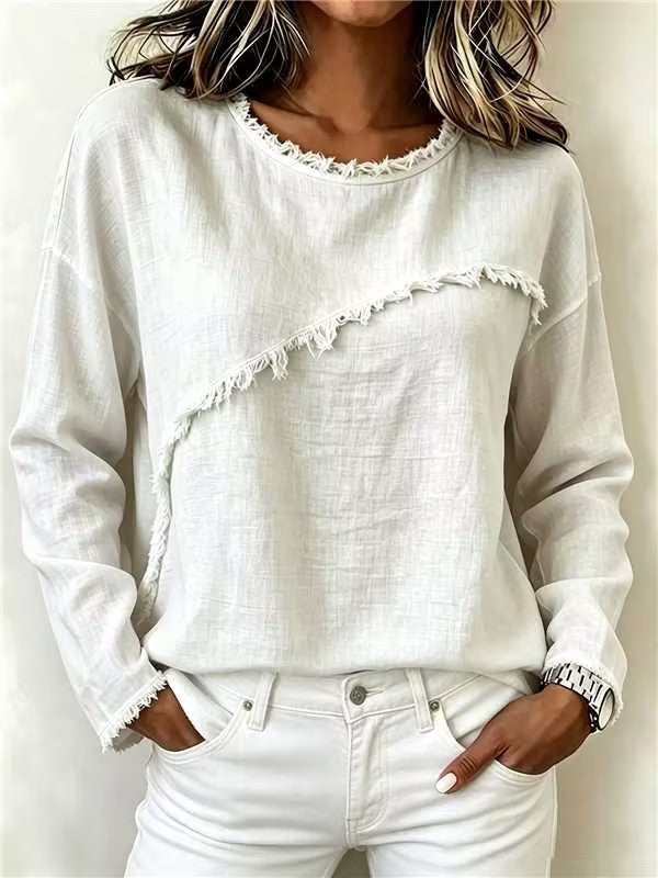 Person wearing a white textured sweater and white pants against a plain background