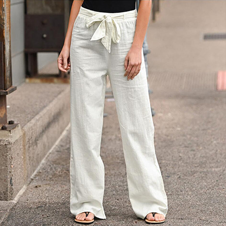 Person wearing light-colored wide-leg pants with a belt on a street.
