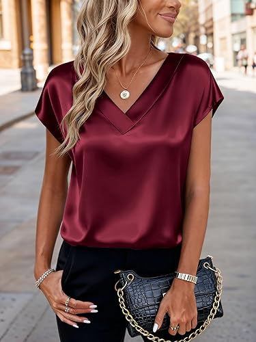 Woman wearing a burgundy satin top with a blurred street background