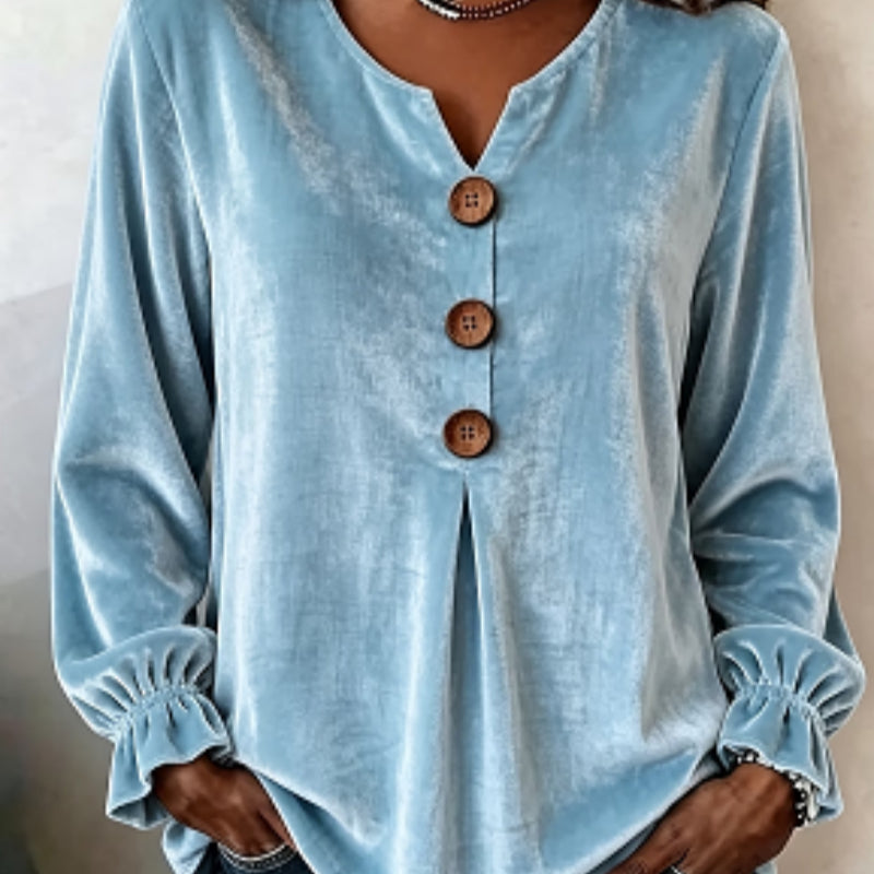 Light blue long-sleeve top with wooden buttons on a neutral background