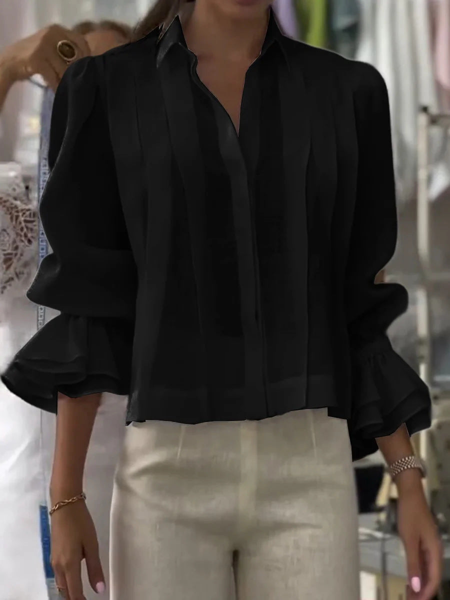 Person wearing a black blouse with ruffled sleeves in an indoor setting
