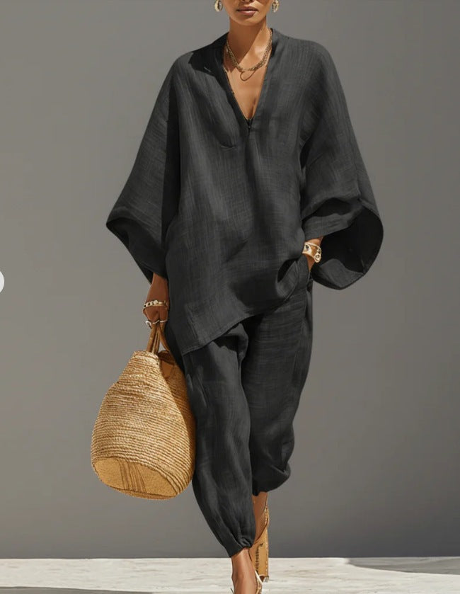 Person wearing a black outfit holding a woven bag against a gray background