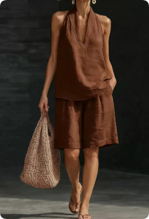 Woman wearing a brown outfit holding a woven bag against a dark background