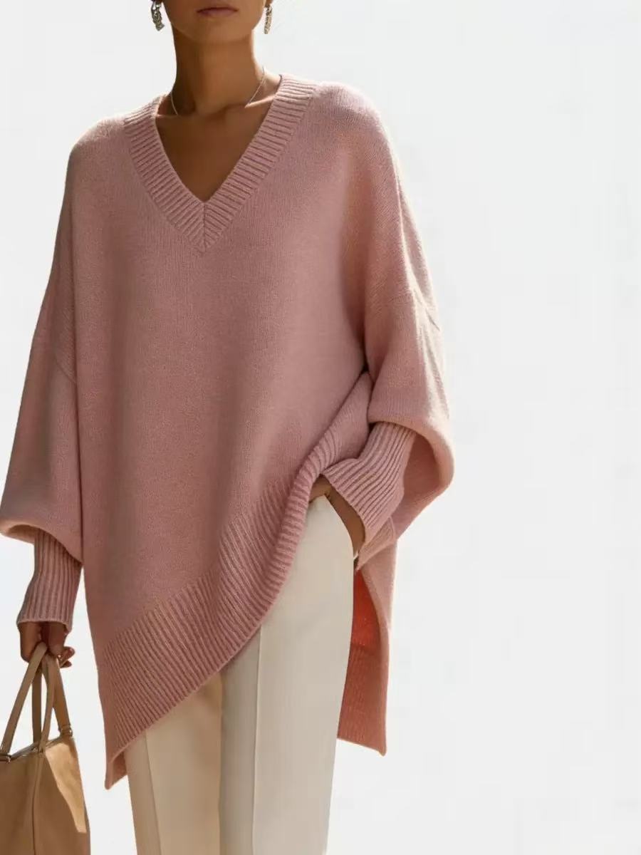 Person wearing a pink poncho over a white outfit on a light background