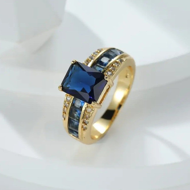 Gold ring with a blue gemstone on a white background