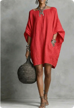 Woman wearing a red dress holding a black textured bag against a gray background