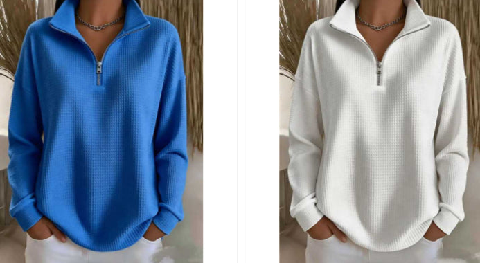 A side-by-side comparison of two women wearing waffle-knit quarter-zip pullovers, one in bright blue and one in white, both styled with white pants and a silver chain necklace.