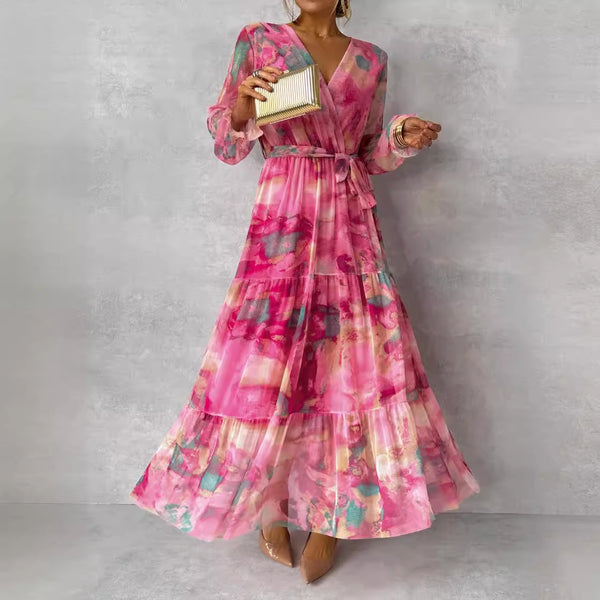 Woman wearing a pink floral dress holding a clutch against a gray background