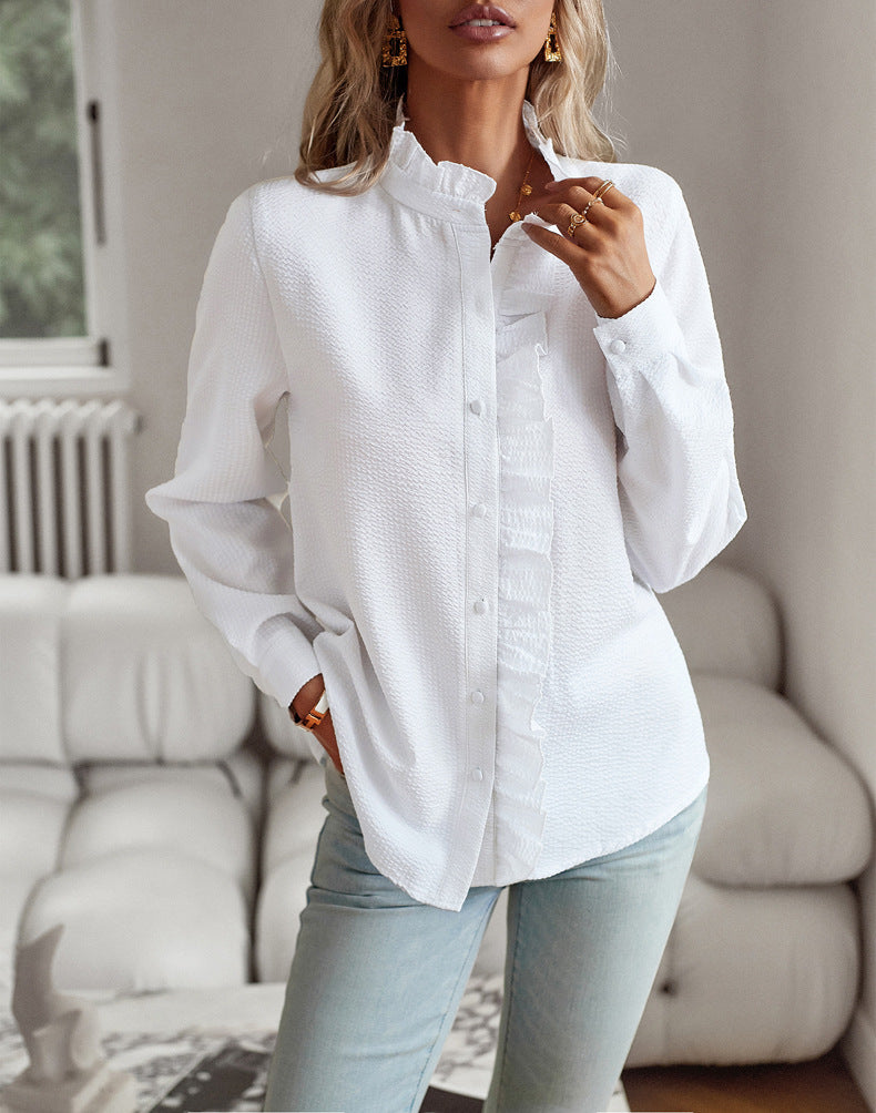 Person wearing a white button-up shirt and light blue jeans in a living room setting.