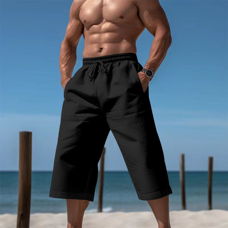 Man wearing black shorts on a beach with clear blue sky