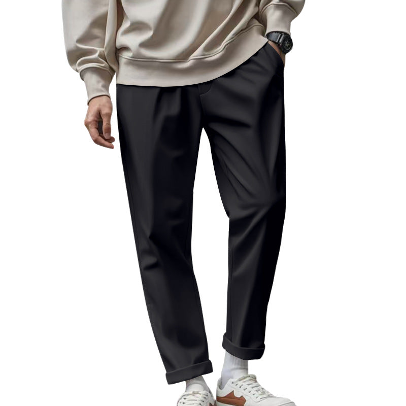 Person wearing black pants and a beige sweater on a white background