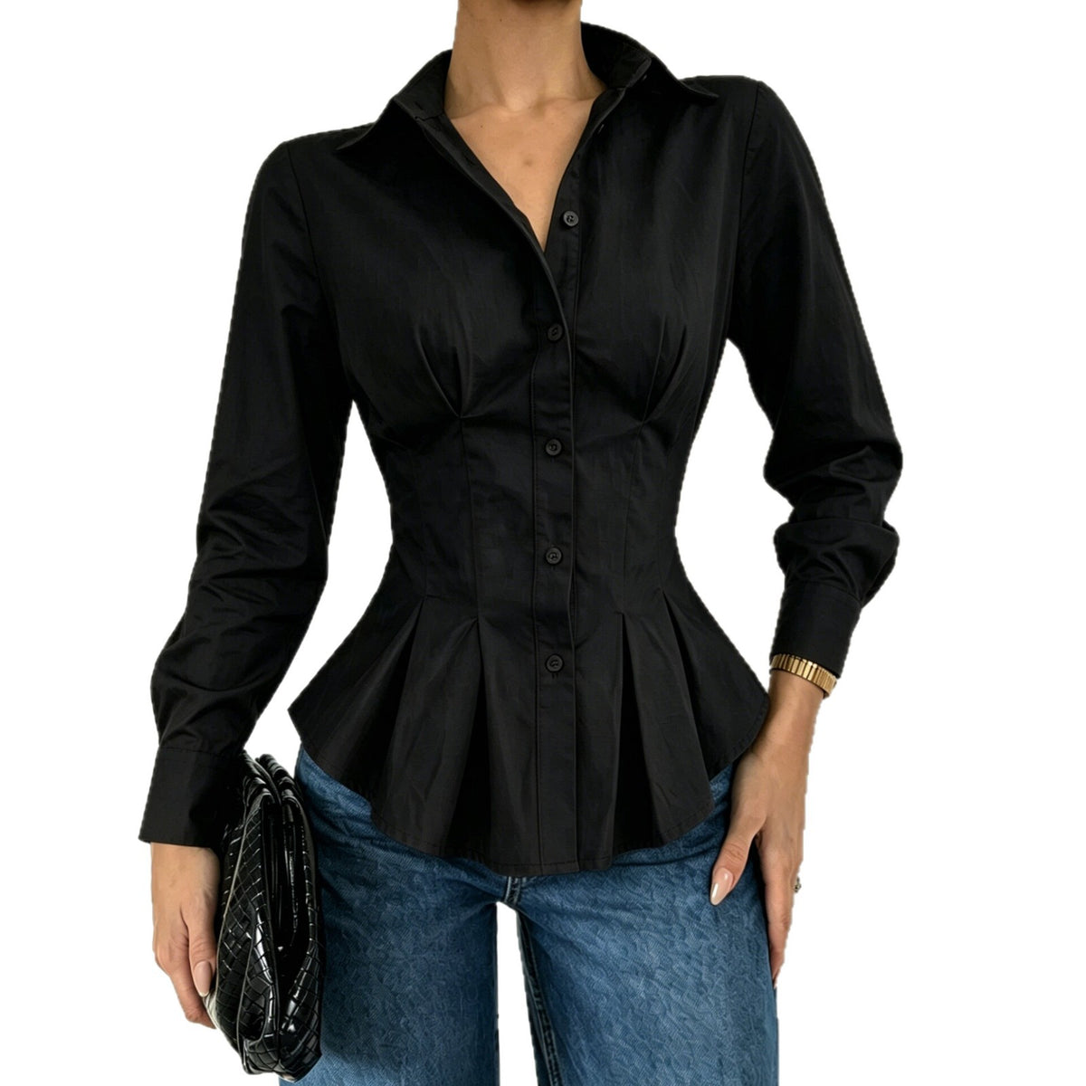 A woman wearing a black long-sleeve button-front blouse with a pointed collar and a peplum waist, paired with blue jeans and holding a black clutch against a plain white background.
