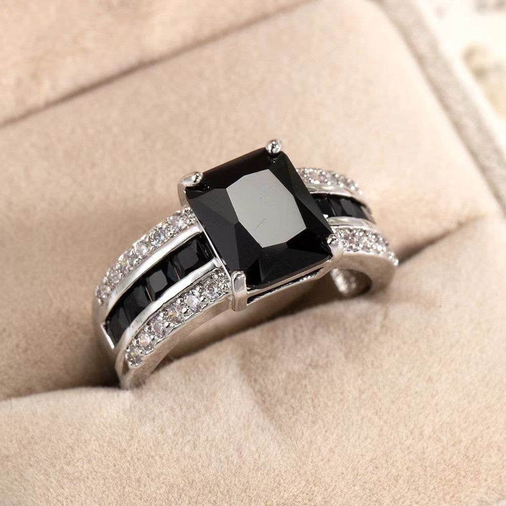 Silver ring with a black gemstone on a beige surface