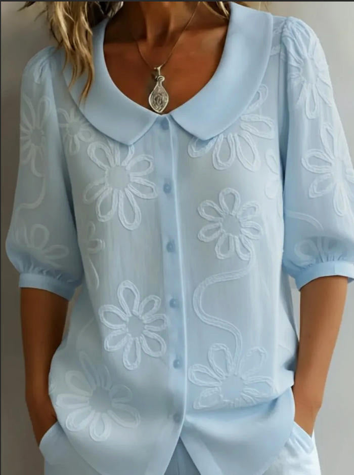 Light blue blouse with floral patterns on a neutral background