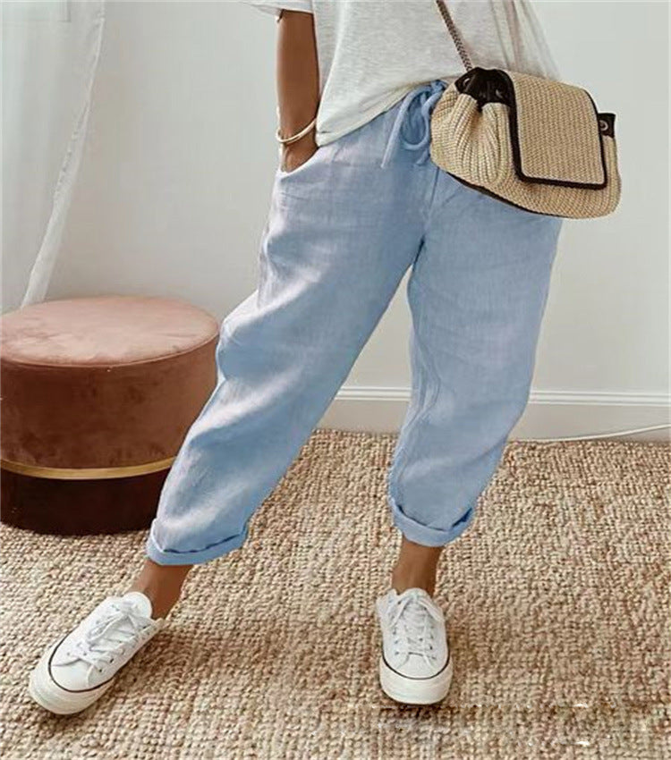Person wearing light blue jeans, white sneakers, and a straw bag on a carpeted floor.
